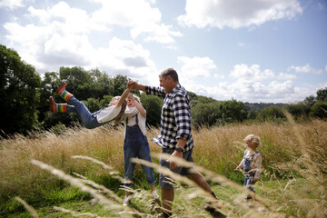 Happy family playing in sunny idyllic rural field