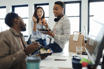 Business people eating takeout lunch at desk in office meeting