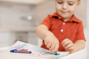 Child boy learn to draw with pencils on paper home, white kitchen background