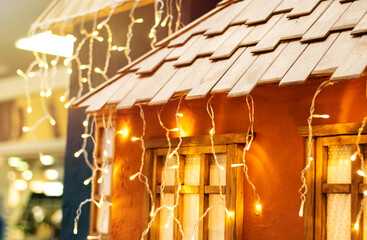 Fototapeta na wymiar Urban Christmas decorations for the facade. Christmas garland lights up on the window of the house. Festive lighting. New Year's decor. European vintage