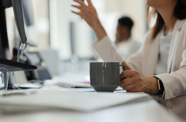 Businesswoman drinking coffee at computer on office desk