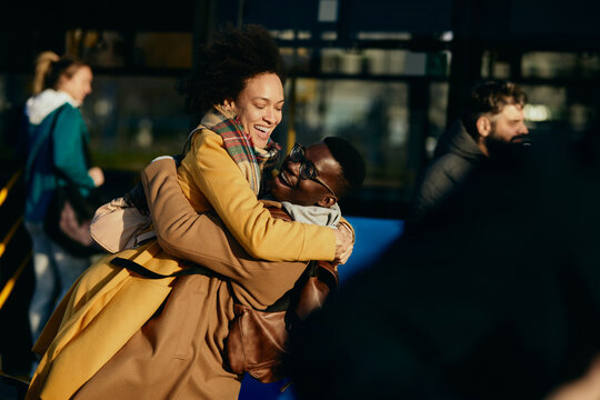 Cheerful African American couple embracing at bus station.