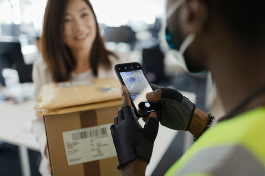 Businesswoman receiving packages from courier with smart phone