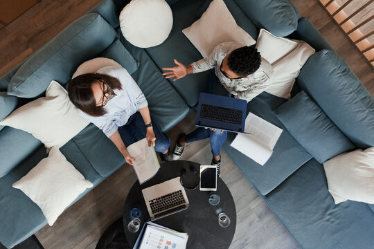Businesswomen with laptops and paperwork meeting on office sofa