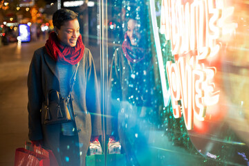 Young woman shopping at urban neon storefront at night