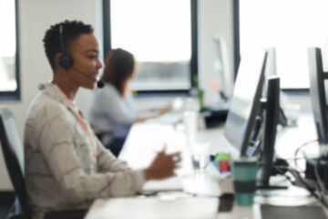 Businesswoman in headset working at computer in call center office