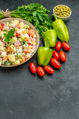 side view of bowl of vegetable salad with vegetables on side with free place for your text on bottom on dark grey background