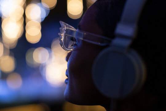 Close up young woman in funky glasses and headphones looking at lights