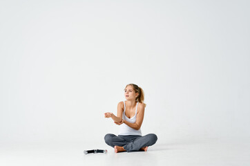Fototapeta na wymiar a woman in sweatpants sits on the floor and looks with displeasure at dumbbells