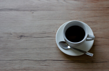 Coffee in white cup on wooden table in cafe with lighting background