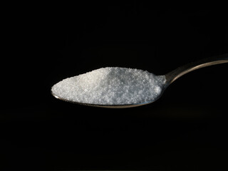 spoon full of sugar on black background