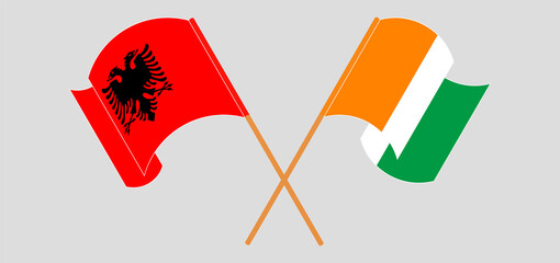 Crossed and waving flags of Albania and Republic of Ivory Coast