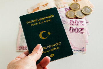 Turkish,green color officer passport in hand on blurred money background,close up taken