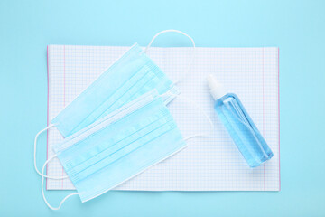 Medicine masks with sanitizer bottle and notepad on blue background