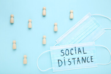 Medicine mask with inscription Social Distance and wooden figure on blue background