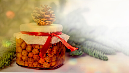 Jar with homemade cloudberry jam on the background of fir branches, the concept of homemade sweets, delicious eco gifts