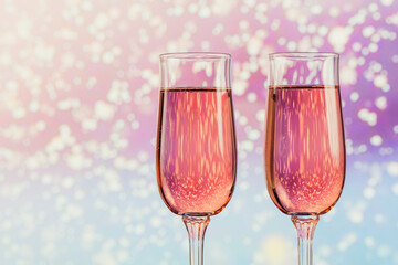 Two glasses of rose champagne with a light snow bokeh as a background. Romantic dinner. Winter, Christmas or New Year holiday concept.