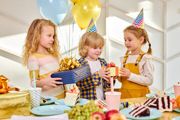 happy birthday party. children in party caps celebrating birthday at home in light room, kids with...