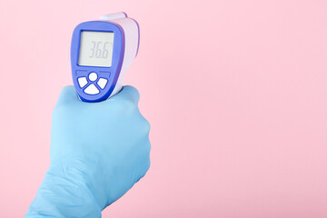 Infrared thermometer in doctor hand on pink background