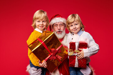Obraz na płótnie Canvas santa claus give gift boxes to children, kids happy to get gifts by santa man, enjoying christmas, celebrating