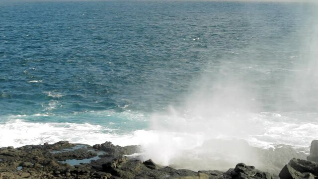 Waves crashing on Galapagos Islands rocks causing blow hole of water