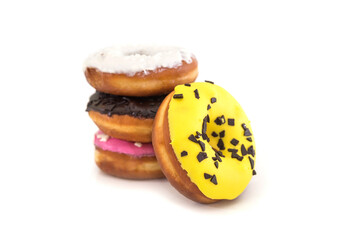  traditional American donuts with chocolate, pink, yellow, white icing and sprinkles on a white plate.