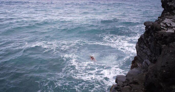 Caucasian woman swimming in ocean near cliff on Maui