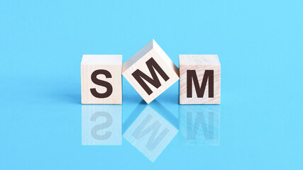 SMM - short for Social media marketing - word is made of wooden building blocks lying on the blue table