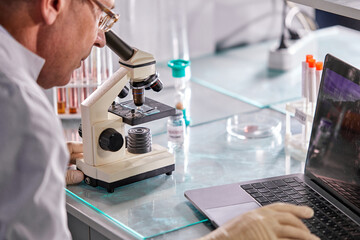 professor male conducts science medical study phamasutical medicine lab in hospital, professional scientist is doing some research vaccine anti-virus Covid-19, using microscope