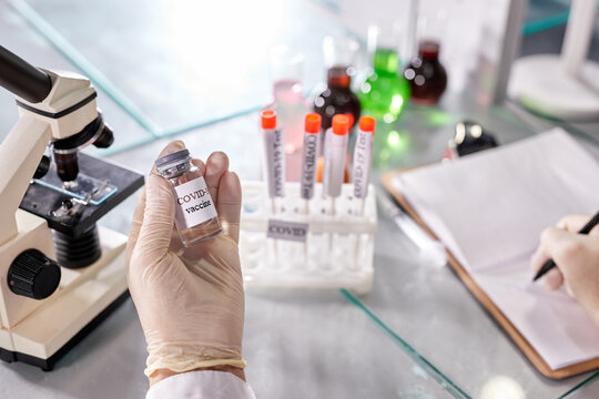 close up doctor's hand in white gloves holding medicine bottle flu, coronavirus, covid-19 vaccine, scientist is preparing for human clinical trials vaccination shot, medicine and drug concept