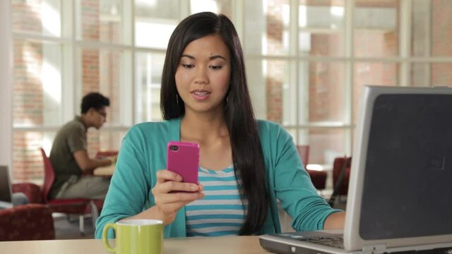 Woman in cafe using laptop and texting on cell phone