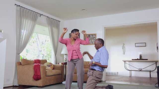 Happy middle-aged Black couple dancing in livingroom