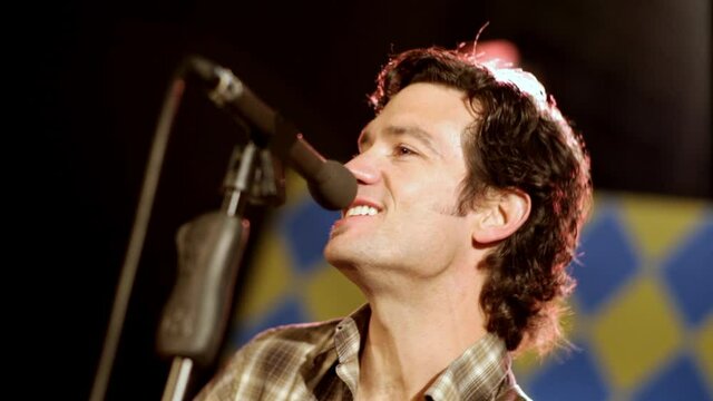 Man on stage playing guitar and singing on stage