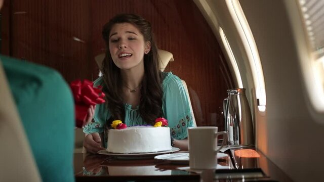 Caucasian woman gives granddaughter cake and gift on private jet
