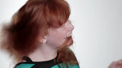 Portrait of laughing girl tossing her red hair