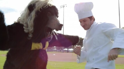 Men in chef and bear costumes dancing on baseball field