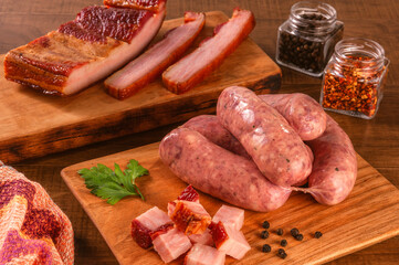 Raw brazilian bacon sausages on the wooden board with fresh cubes of bacon and spices - Linguiça de bacon