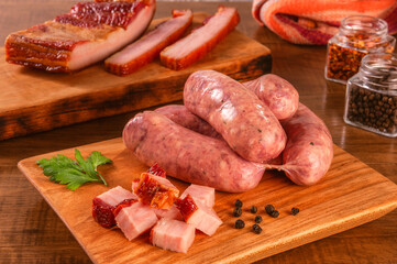 Raw brazilian bacon sausages on the wooden board with fresh cubes of bacon and spices - Linguiça de bacon
