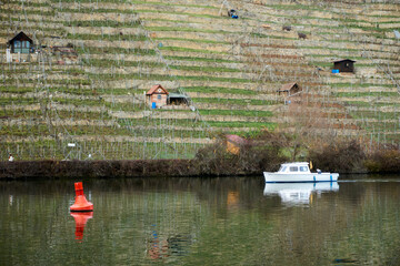 A red buoy and white boat driving by the small house in the hill on the neckar river