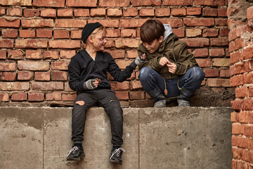 two friendly street boys sharing piece of bread, eating together, beggars in dirty clothes...