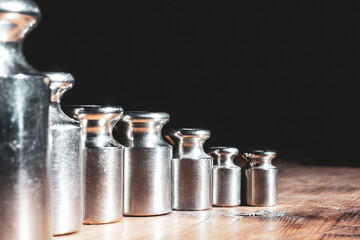 set of small weights for jewelry scales on a wooden table. front and background blurred with bokeh...