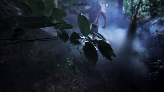 Rear view of frantic friends running in foggy woods at night