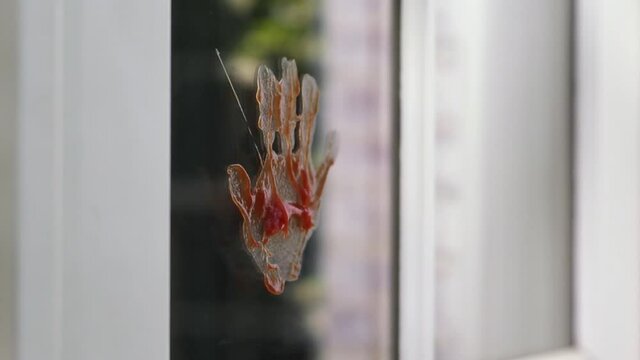 Close up of hand leaving messy ketchup hand print on window