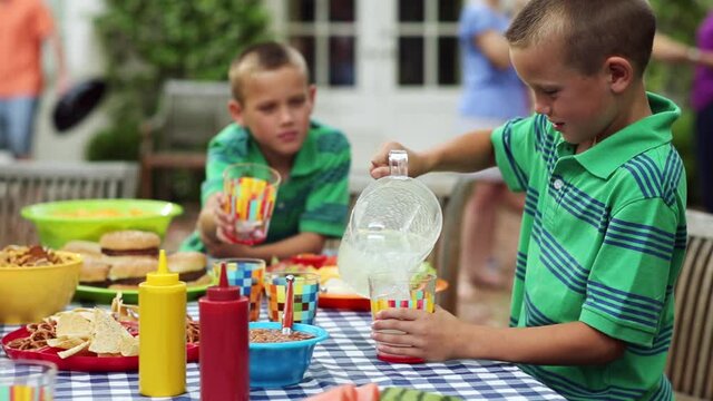 Caucasian twin brothers laughing while spilling lemonade
