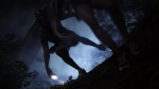 Friends running down foggy hill in woods at night