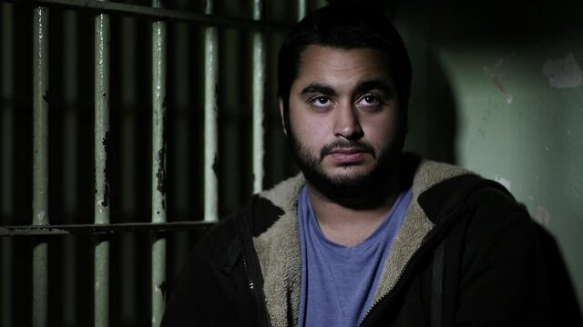 Close up of man sitting in dark jail cell