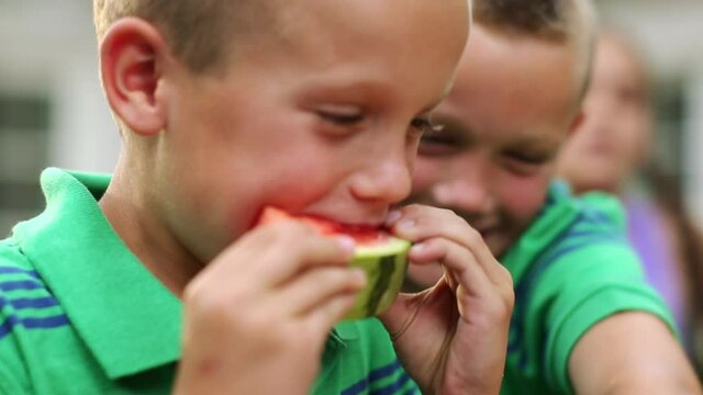 Caucasian children running to eat watermelon