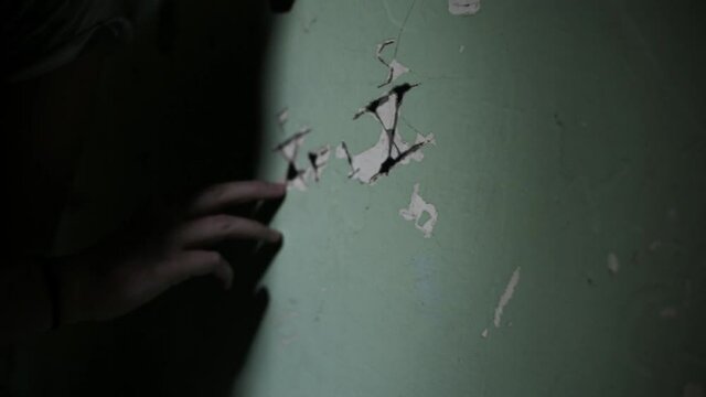 Close up of Caucasian teenage girl tracing finger on wall in jail cell