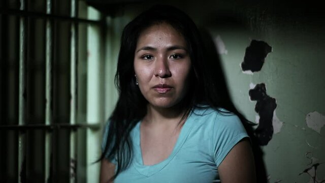 Portrait of Hispanic woman in dark jail cell