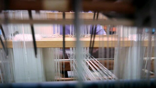 Close up of woman using loom to weave fabric